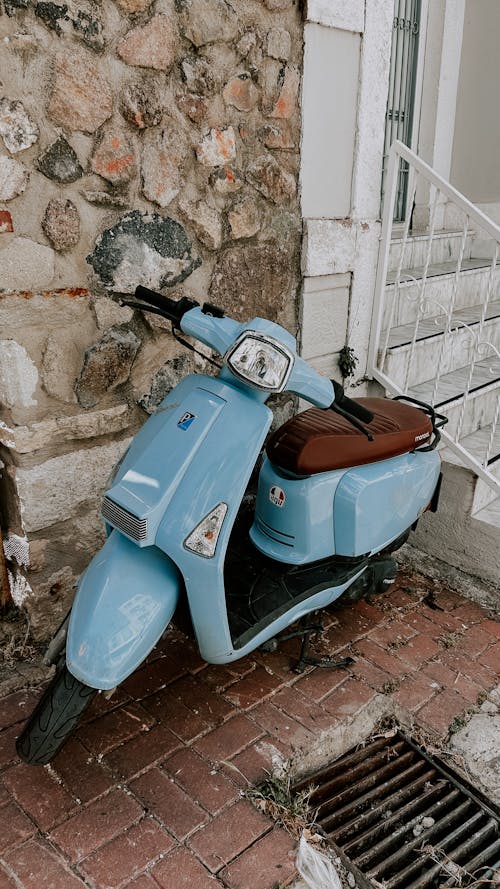 A blue moped parked on a cobblestone street