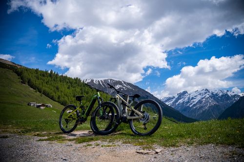 Free Parked mountain bikes under a blue sky with the snowcapped Alps in Livigno, perfect for summer adventures. Stock Photo