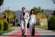 Stylish couple walking confidently on red carpet outdoors in elegant fashion.