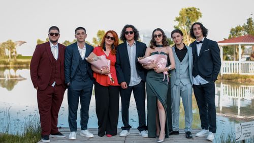 Free A group of people dressed formally celebrating outdoors by a lakeshore. Stock Photo
