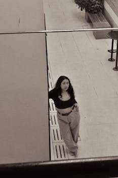 Stylish woman with long hair poses in front of a wall in an urban environment. Black and white photo.