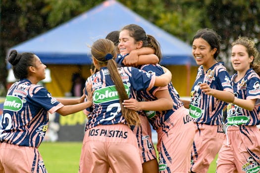 Teenage girls' soccer team celebrating a victory on the field outdoors.