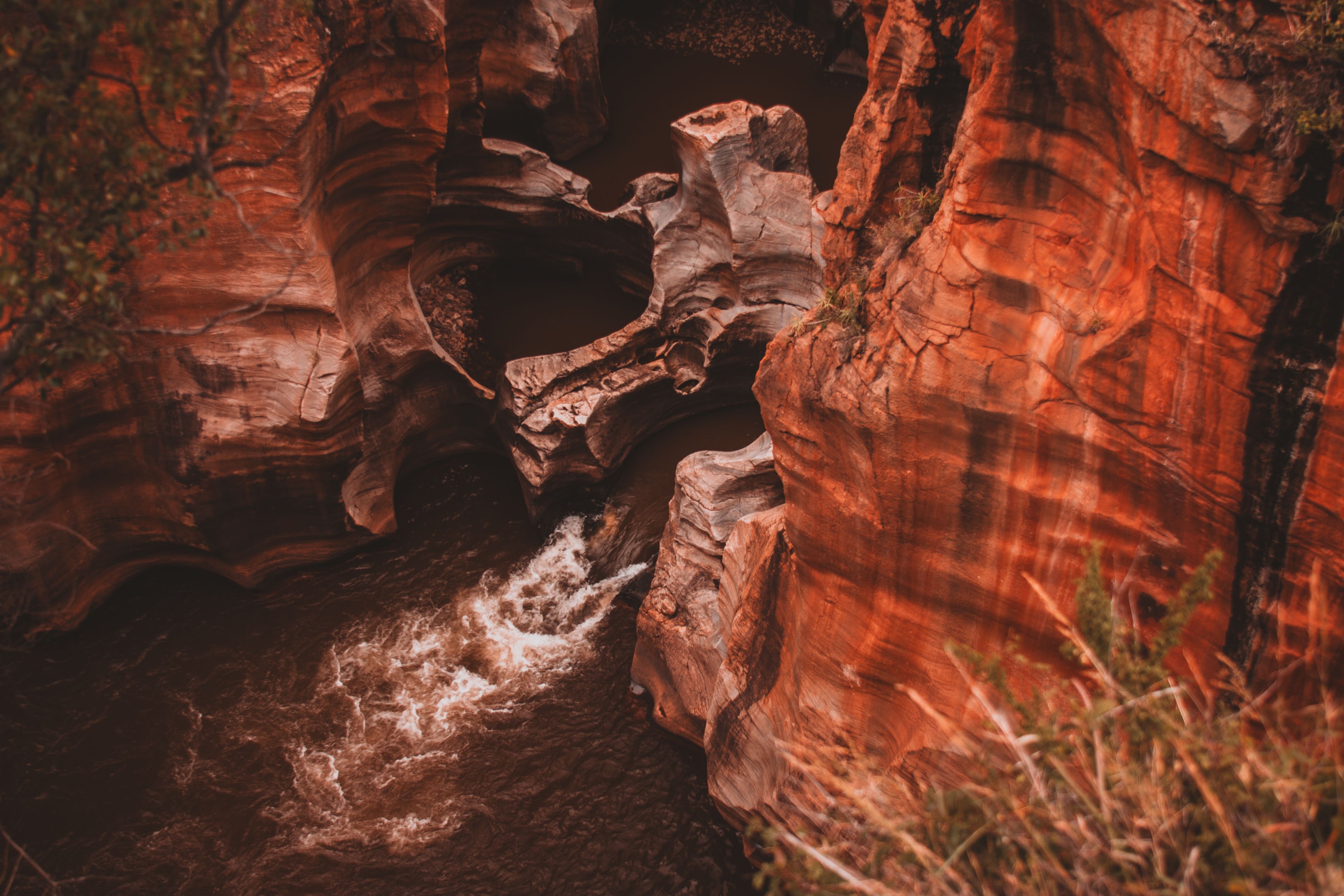 Discover the dramatic red rock canyon with flowing rapids, showcasing nature's powerful erosion.