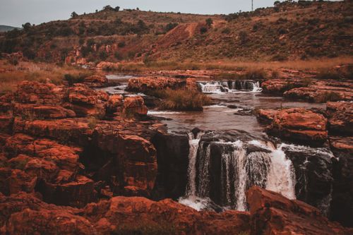 Free Captivating scene of cascading waterfalls in a red rock canyon during sunset. Stock Photo