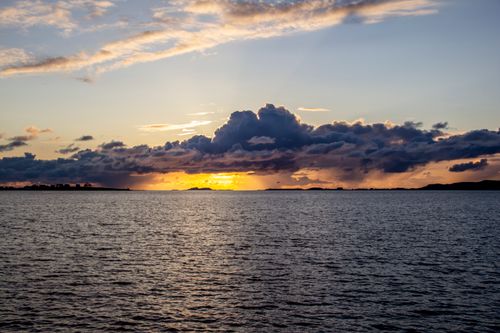 Free A breathtaking sunset with golden clouds over a calm sea, perfect for peaceful and tranquil themes. Stock Photo