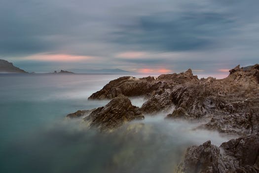 这张黄昏时分长时间曝光拍摄的岩石海岸线照片，以宁静的海景为特色，突出了海洋的运动