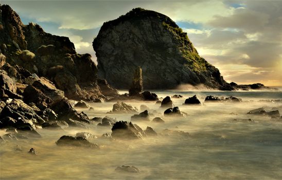 日落时分，海浪拍打着令人惊叹的岩石海岸，天空呈现出戏剧性的景象