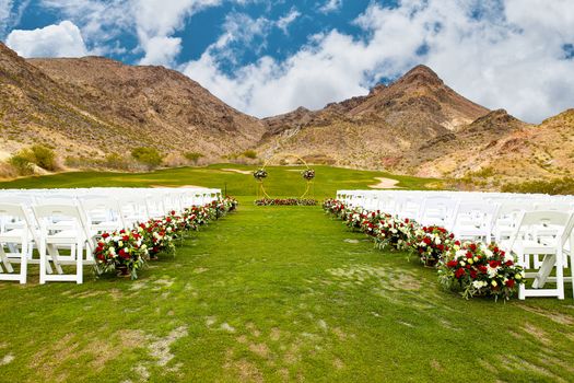 Beautiful outdoor wedding setup with flowers and arch against mountain backdrop.