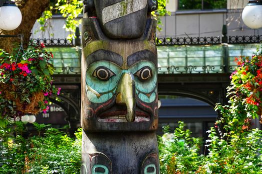 Detailed image of a colorful totem pole surrounded by lush greenery in a vibrant outdoor setting.