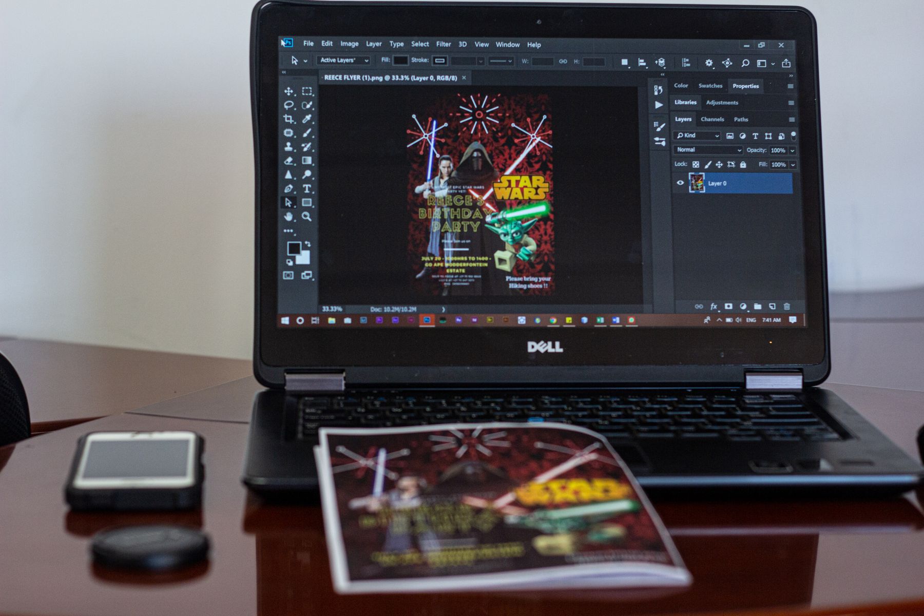 A laptop displaying a flyer design in progress in a workspace