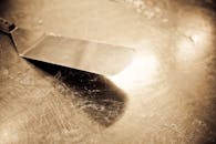 一把复古不锈钢抹刀的特写镜头，呈棕褐色，放在破旧的台面上