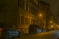 夜晚，城市街道两旁停满了汽车，路灯照亮了灯火通明的建筑物