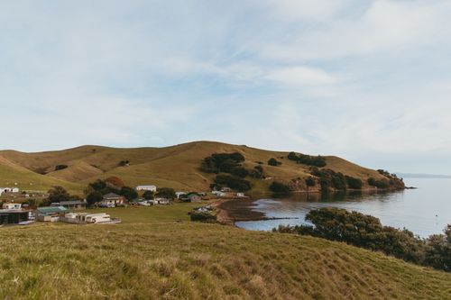 Free Beautiful coastline and village view with rolling hills in Kereta, Waikato, New Zealand. Stock Photo