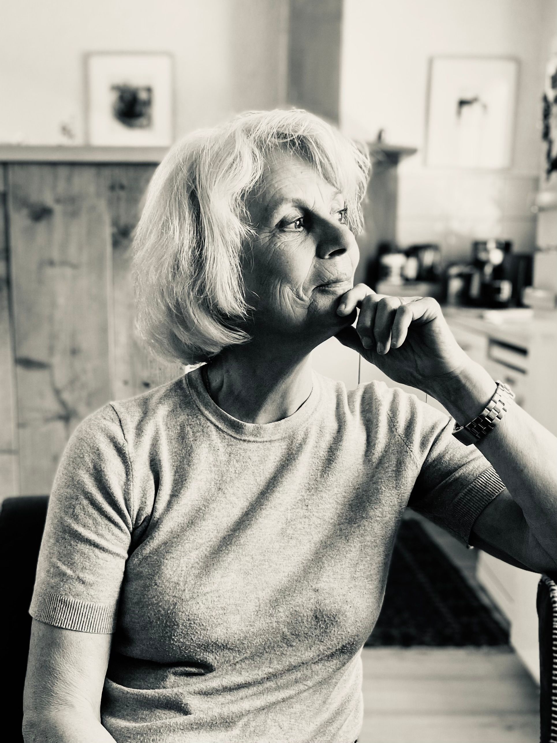 Black and white portrait of a senior woman contemplating indoors with a serene expression.