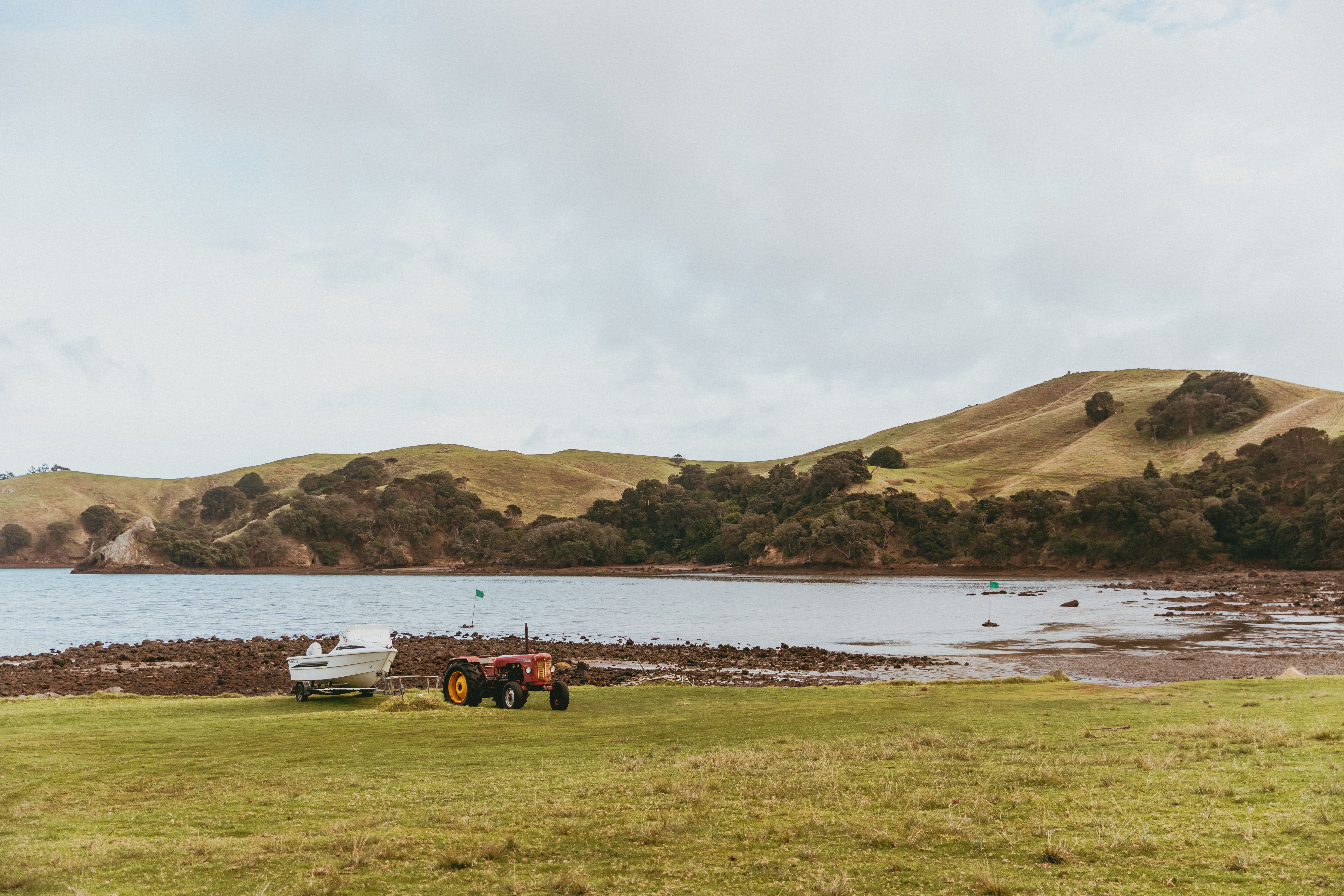 Serene landscape of a coastal bay with tractor and boat on the Coromandel Peninsula, New Zealand.