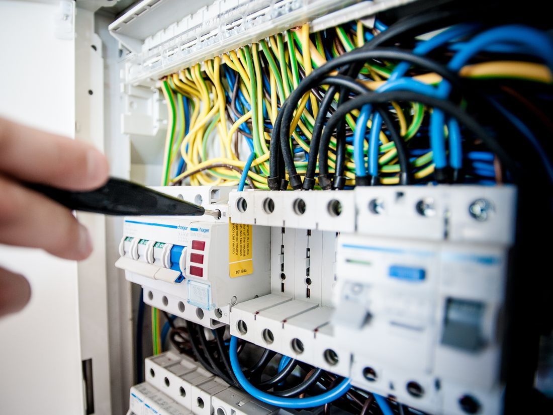 Electrician working on a circuit breaker panel with colour-coded wiring