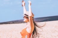 一位身着夏裙的妇女无忧无虑地举起胳膊，在户外享受阳光明媚的日子