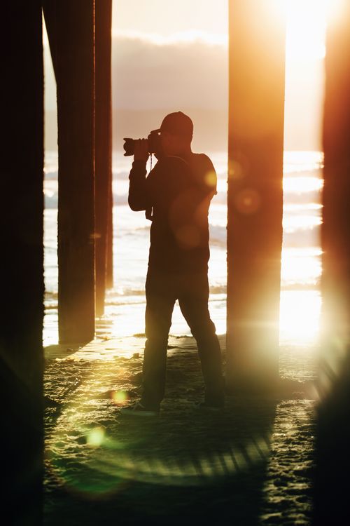 Free Silhouette of a photographer taking pictures at sunset under Pismo Beach Pier, California. Stock Photo