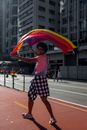 Woman in White T-shirt and Blue and White Plaid Skirt Holding Multi Colored Umbrella