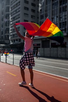 在巴西圣保罗的一场骄傲活动中，一个快乐的人挥舞着彩虹旗