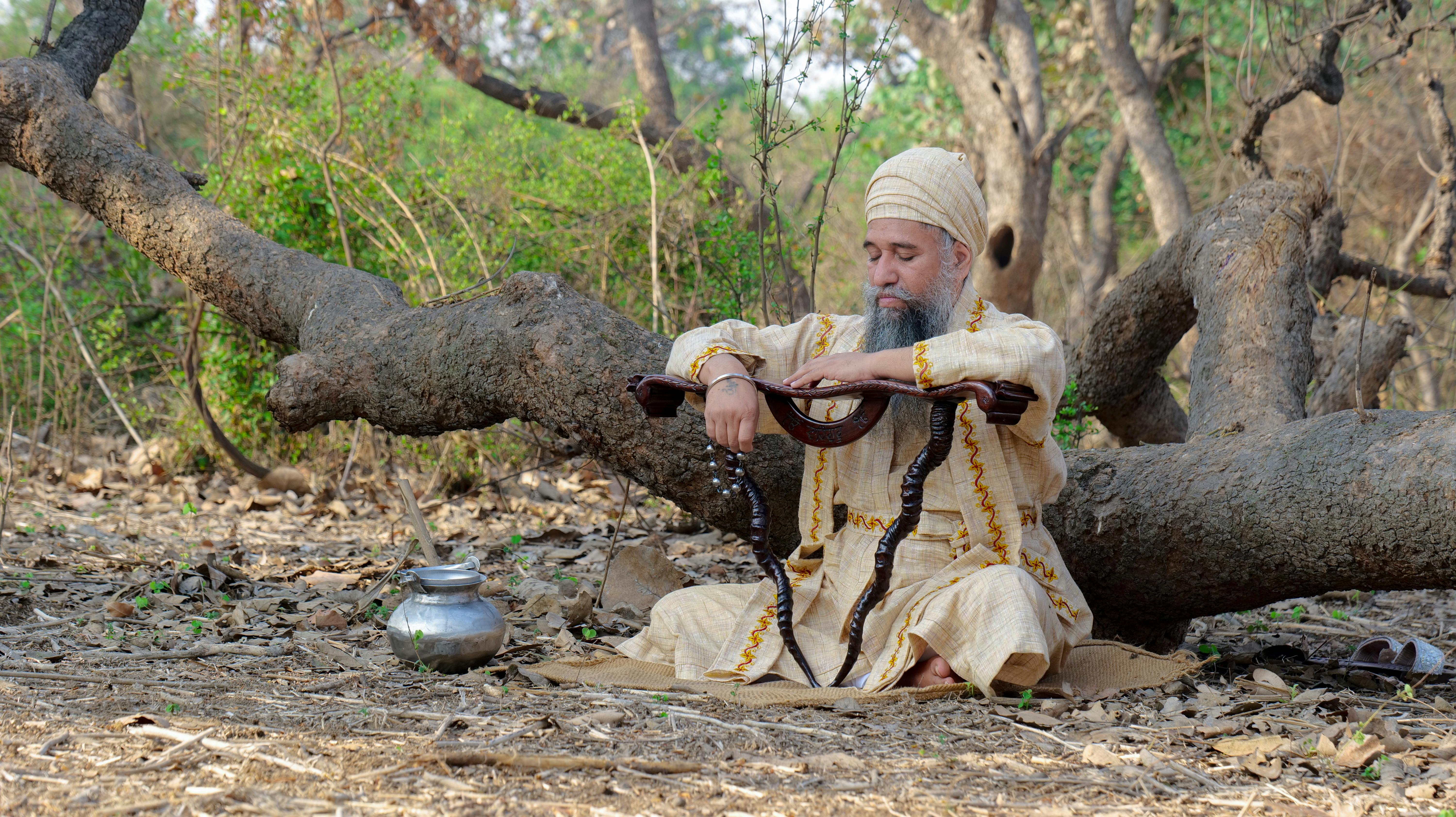 A saddhu with a snake relaxes in a peaceful forest in Maksudra, India, embodying spirituality.