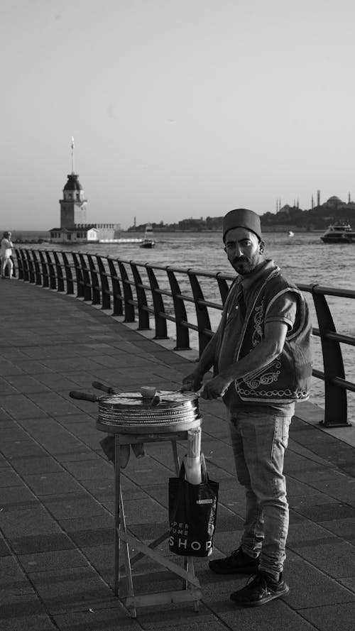 A man is standing on a pier with a grill