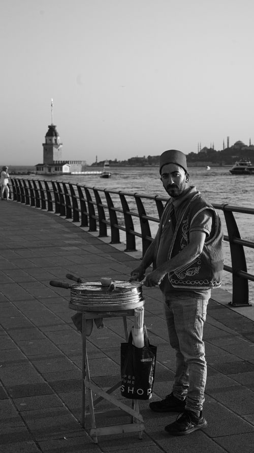 Free A street vendor in traditional attire near Istanbul's Maiden's Tower, scenic Bosphorus view. Stock Photo