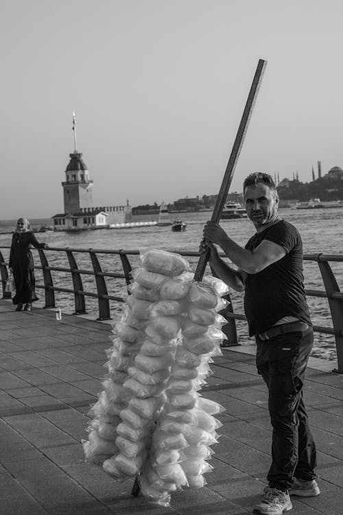 A man is holding a large piece of cloth on the pier