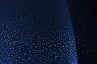 宏观镜头捕捉了深蓝色潮湿表面上的水滴，突出纹理