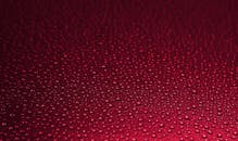 水滴在红色纹理表面特写，形成迷人的图案