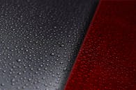 水滴在红黑对比鲜明的表面上的生动特写，创造出引人注目的视觉效果