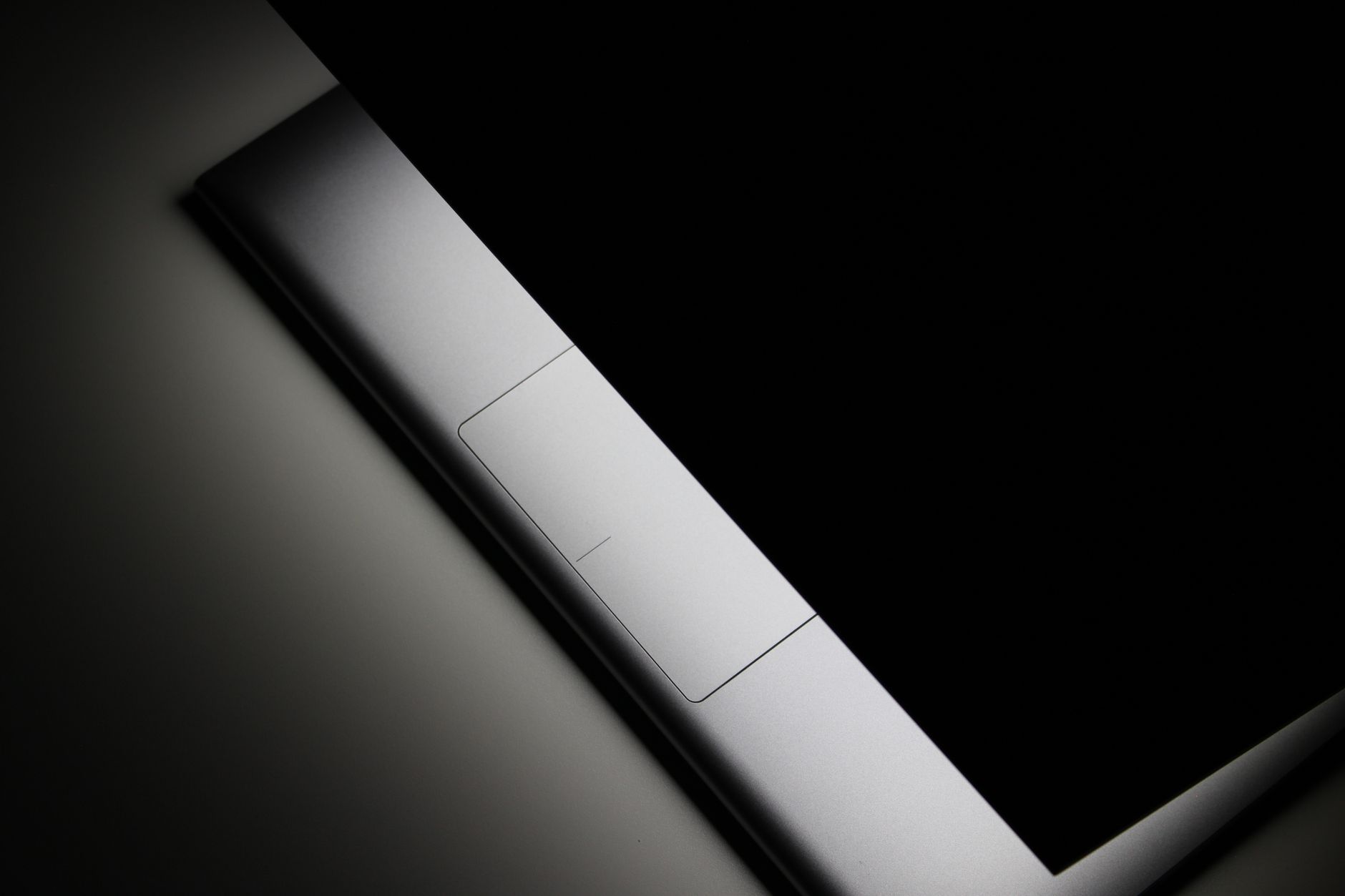 Sleek minimalist closed laptop presented in a moody dark studio setting with a focus on design.
