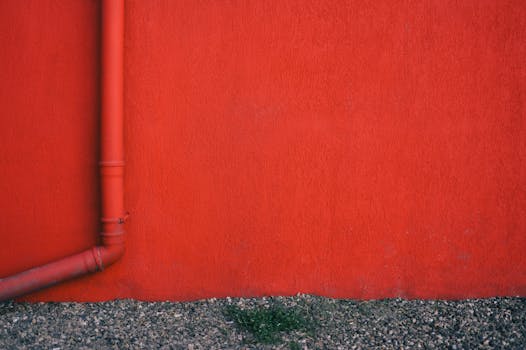 Bold red wall with a metal pipe and gravel base, perfect for textures.