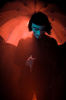 An enigmatic silhouette of a person wearing a mask holding an umbrella in moody lighting.