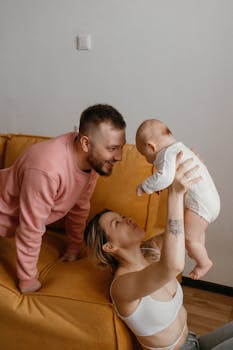 A happy family scene with parents playing with their baby indoors, showcasing love and togetherness.