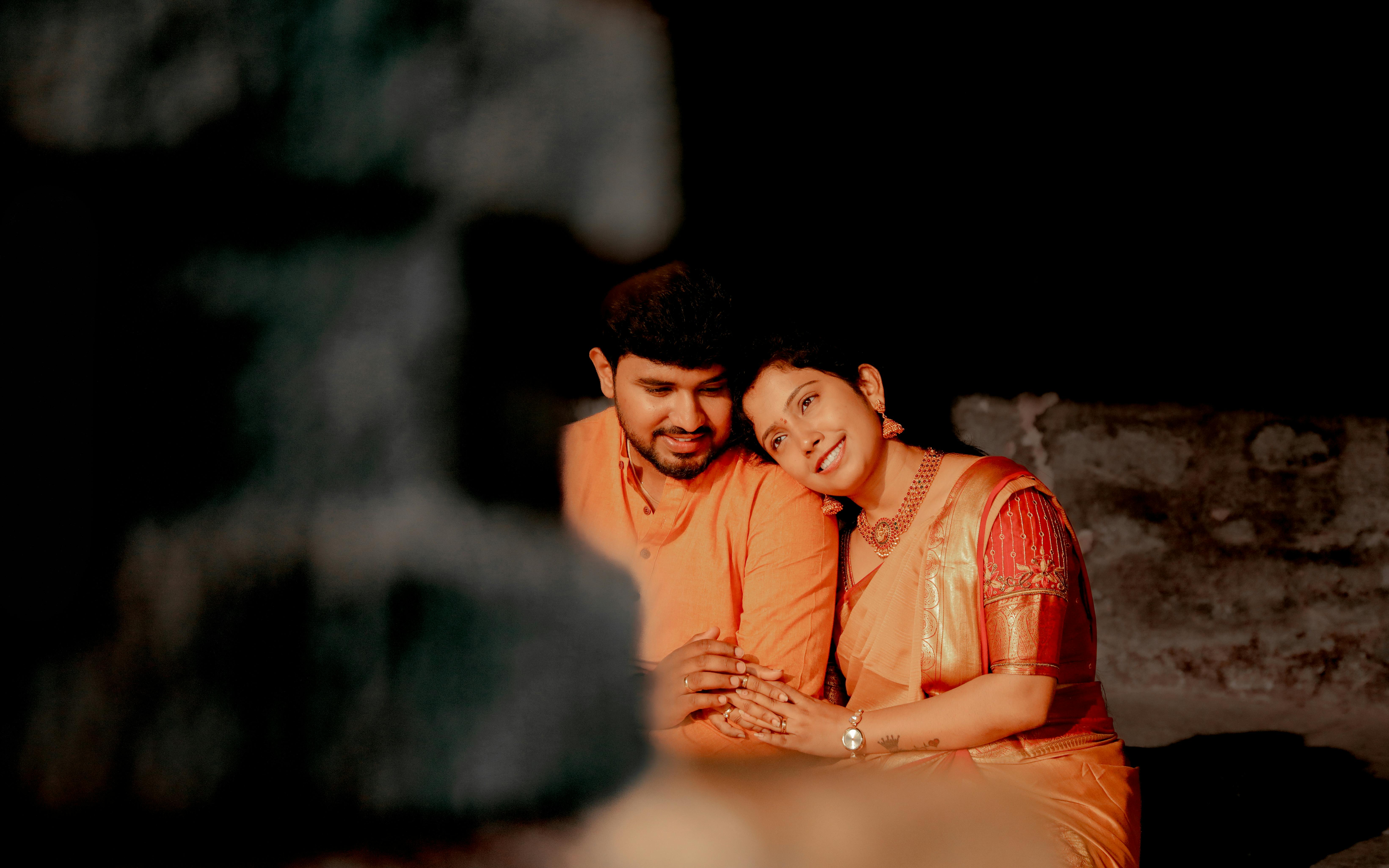 A couple in traditional Indian clothing shares a loving moment indoors, highlighting cultural elegance.