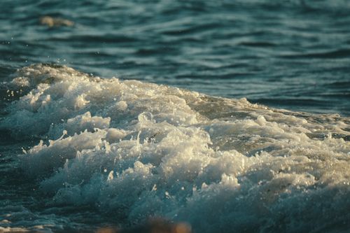 Free Close-up of ocean waves crashing on the shore at sunset, capturing the power and beauty of nature. Stock Photo