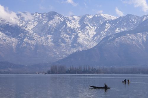 Free A serene view of boats on Dal Lake with snowcapped mountains in Srinagar, India. Stock Photo