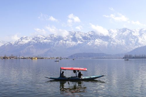 Free A tranquil scene of a boat on Dal Lake, framed by the snowcapped Himalayas in Srinagar. Stock Photo