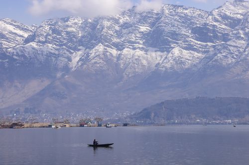 Free Tranquil scene of a boat on Dal Lake with snow-capped Zabarwan mountains in Srinagar. Stock Photo