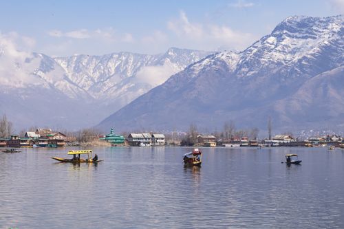 Free Picturesque Dal Lake in Srinagar with shikaras and snow-capped mountains in the background. Stock Photo