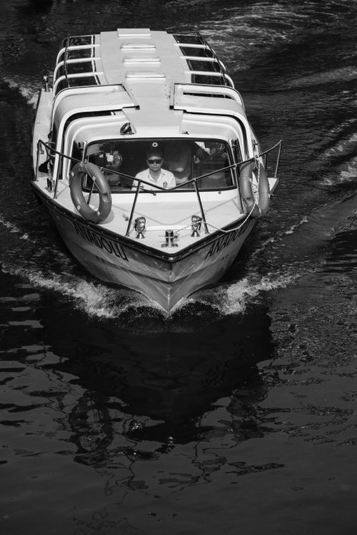 Free A captain navigates a tour boat through open water, captured in a dynamic black and white image. Stock Photo