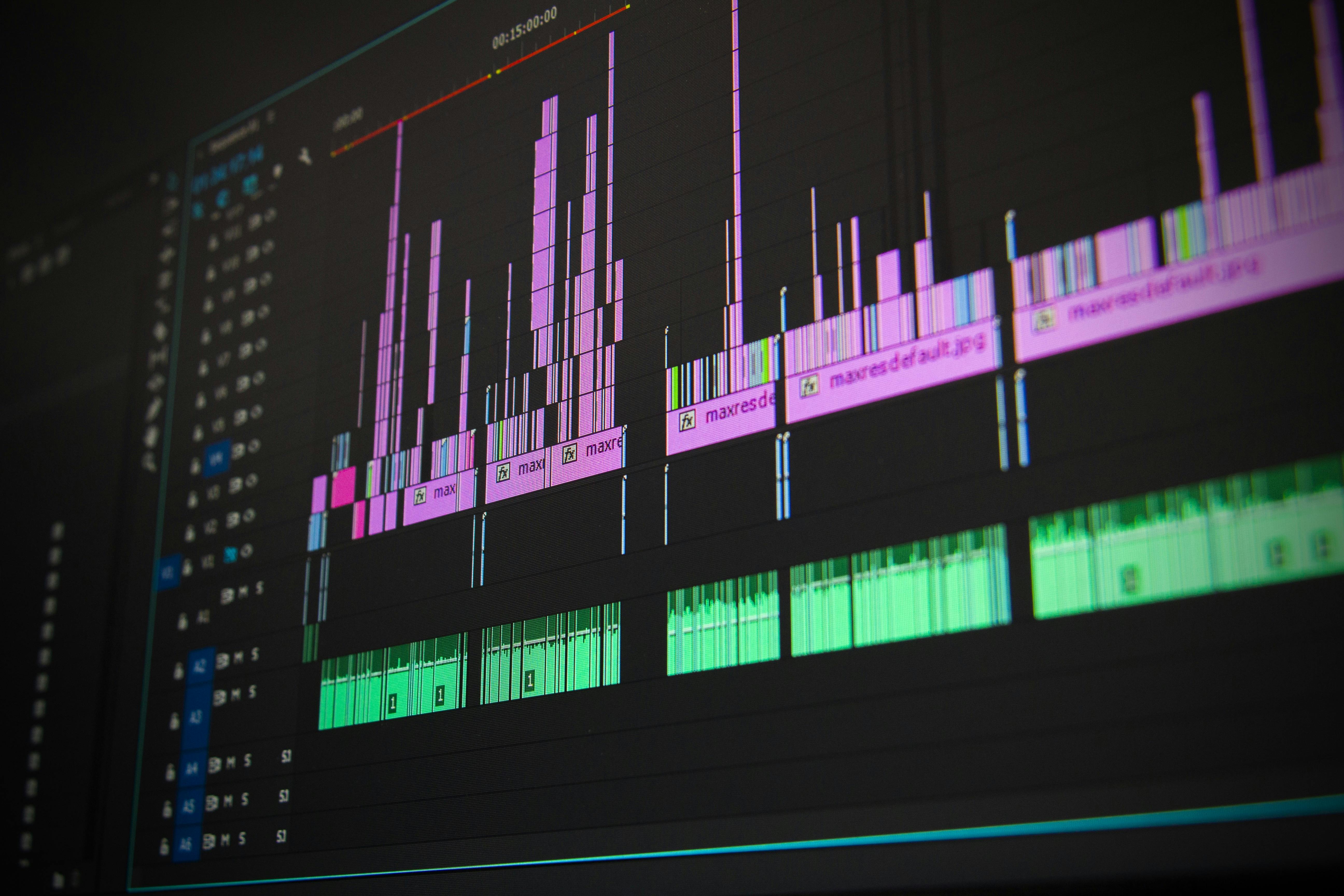 a video editing timeline displaying pink and green audio and visual tracks on a dark screen.