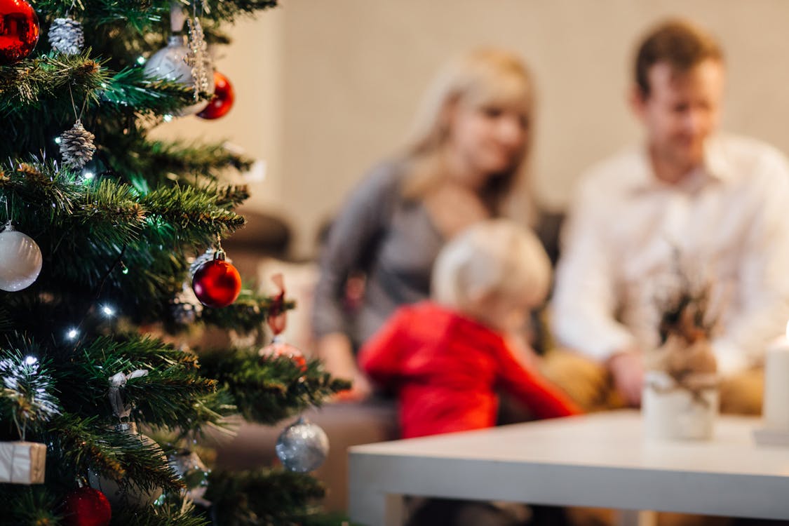 Free A cozy family gathering by the Christmas tree, enjoying festive decorations. Stock Photo