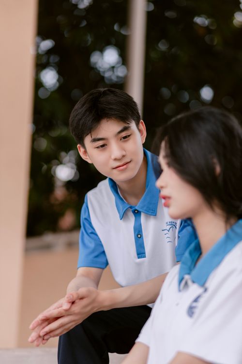 Free A young Asian couple in blue polo shirts sharing an affectionate moment outdoors. Stock Photo