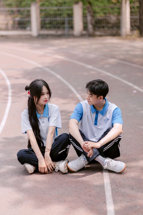 Free Teenagers sitting on a sports track in matching blue and white uniforms, symbolizing friendship and teamwork. Stock Photo