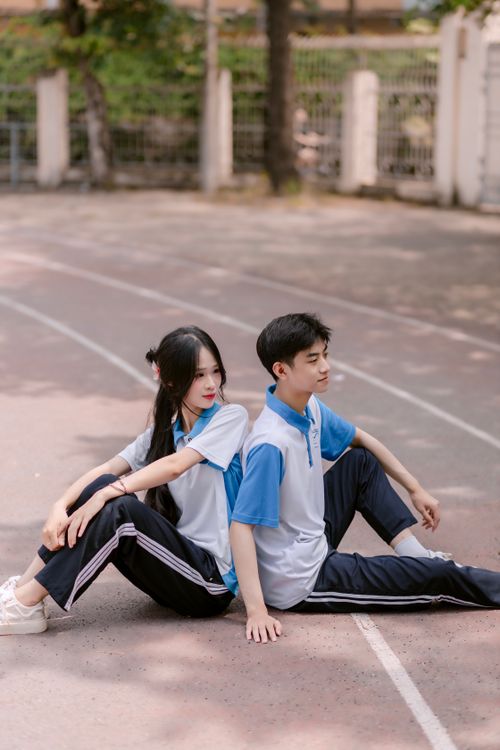 Free Young couple in matching sportswear sitting on an outdoor track, enjoying a relaxing moment together. Stock Photo