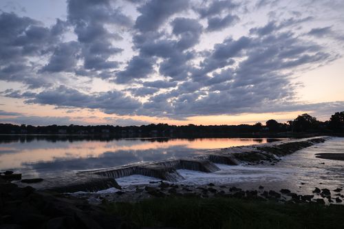 Free A tranquil evening view of a dam and lake in Stamford, CT during a colorful sunset. Stock Photo