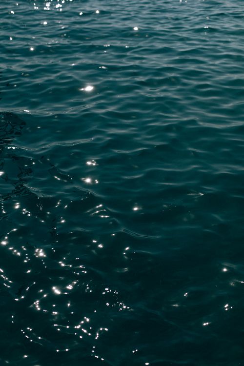 Free Glistening ocean surface with sunlit ripples and reflections creating a serene atmosphere. Stock Photo
