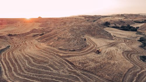 Free An aerial view of a picturesque farmland at sunset, showcasing a harvester amidst vast fields. Stock Photo